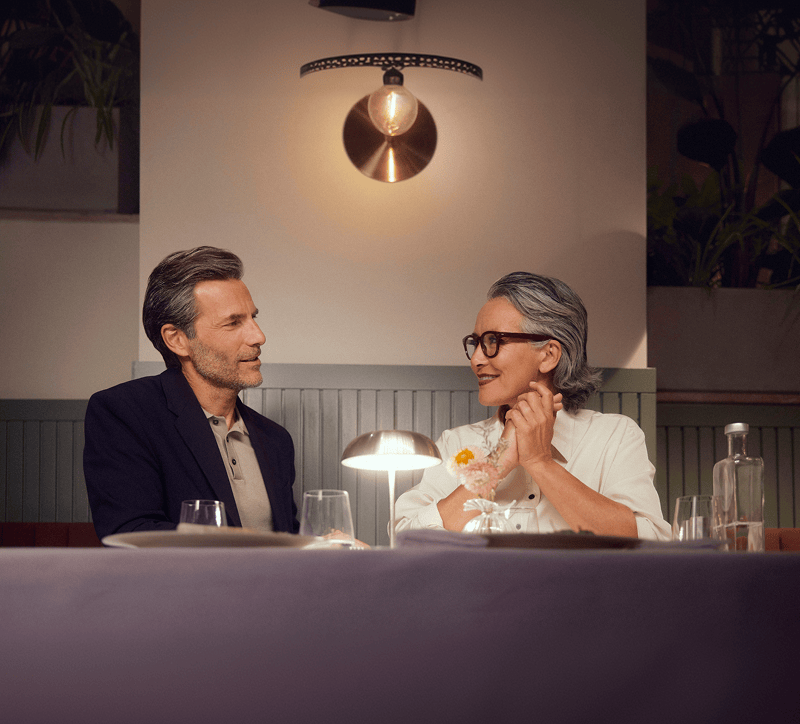 Two people sitting at a table in a restaurant, engaged in conversation.